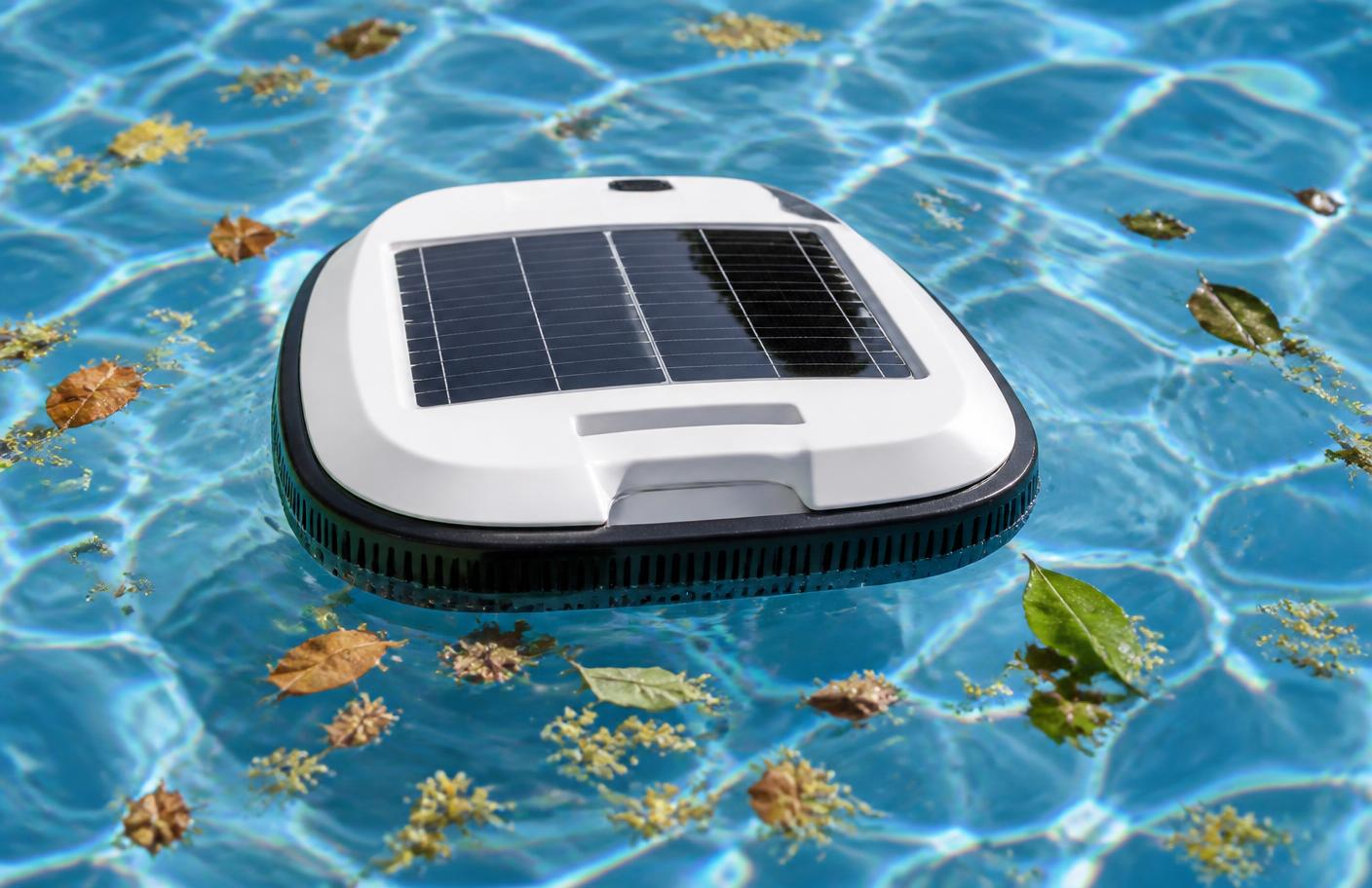 A solar powered robotic pool surface skimmer floating on a swimming pool collecting fallen leaves and pollen. Image by www.CleaningRobots.Online.
