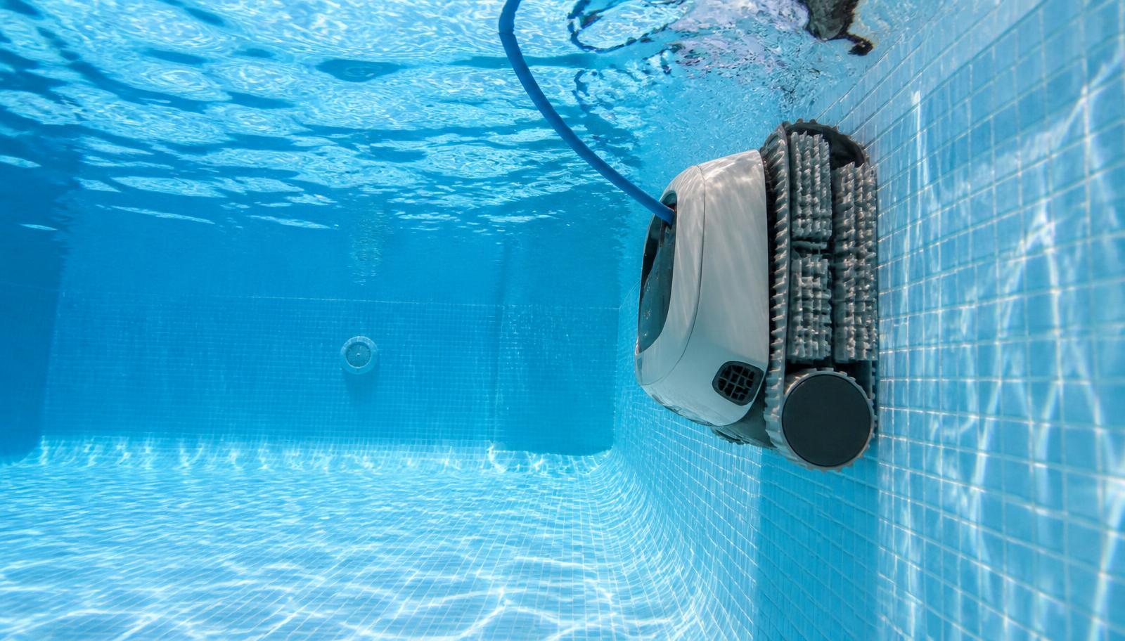 A robotic pool cleaner submerged and crawling along the floor of a backyard swimming pool. Image by www.CleaningRobots.Online.